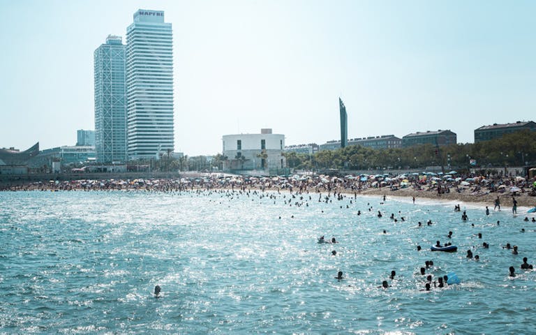 POPULÆR MØTEPLASS: På bystranden i Barcelona kan du slappe av i bølgene, samtidig som du har kort vei til alle tilbudene i storbyen. Foto: Getty Images