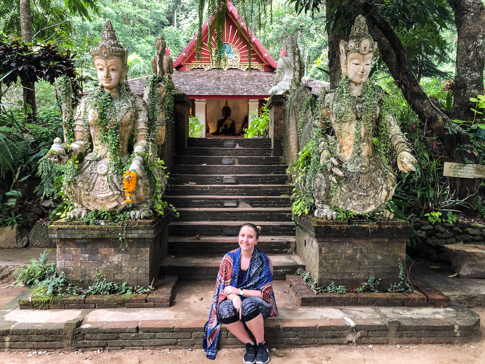 Ung kvinne sitter med et sjal over skuldrene foran et tempel