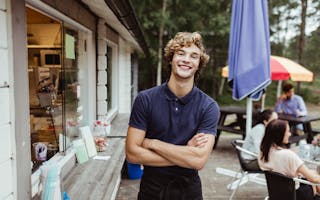 Smilende ung mann foran kiosk på campingplass
