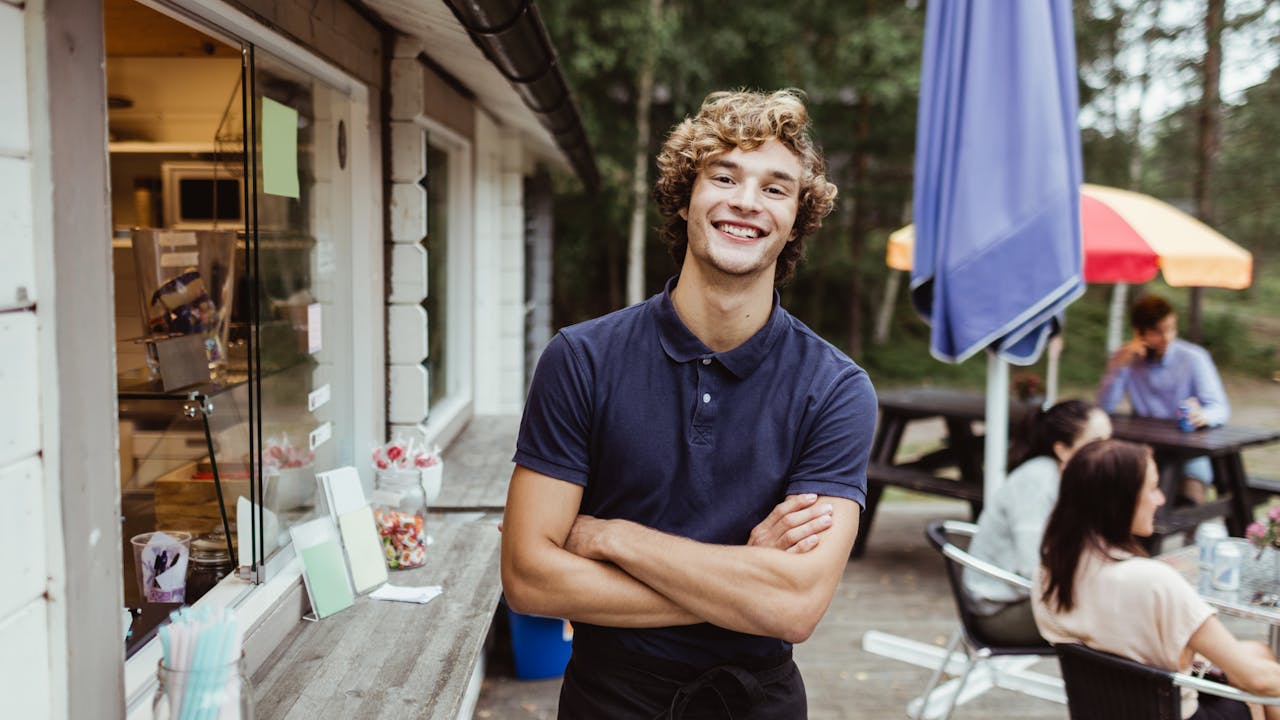 Smilende ung mann foran kiosk på campingplass