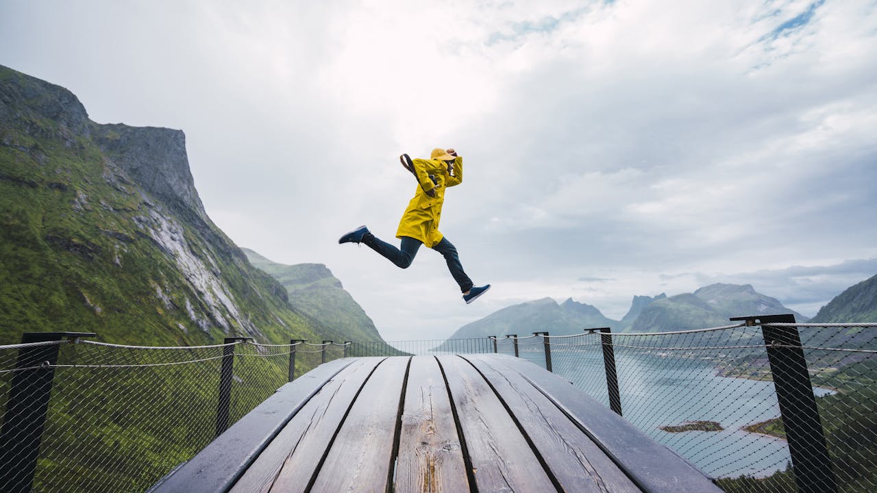Person med gul jakke hopper ved utsiktspunkt
