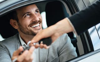 Mann i bil får nøkler av bilselger