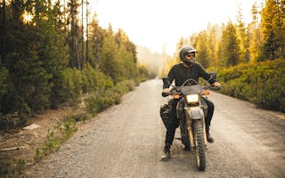 Mann på motorsykkel i skogen