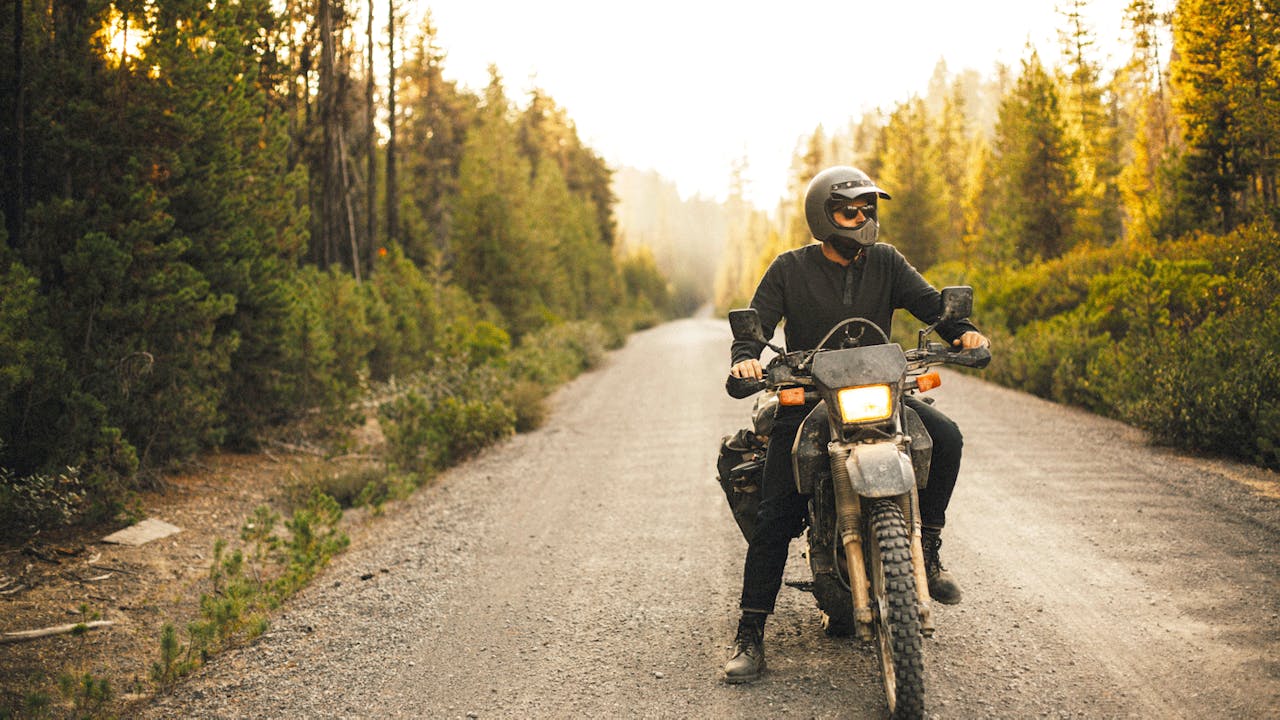 Mann på motorsykkel i skogen