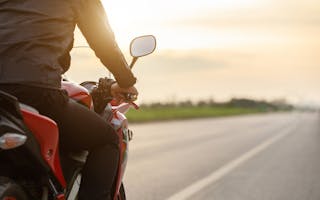 Mann på motorsykkel i solnedgang