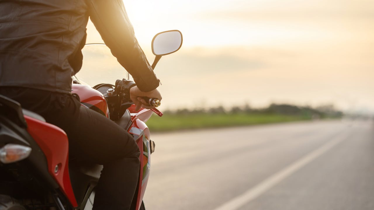 Mann på motorsykkel i solnedgang