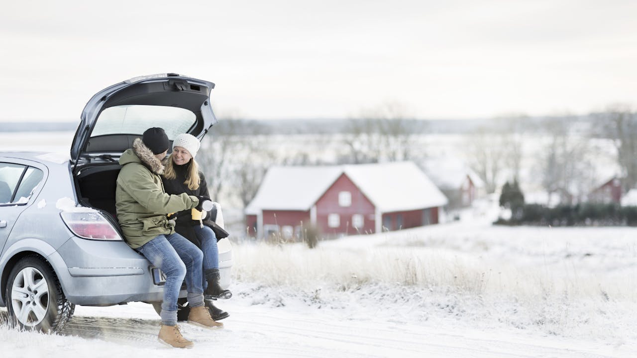 Par sitter i enden av en bil i vinterlandskap