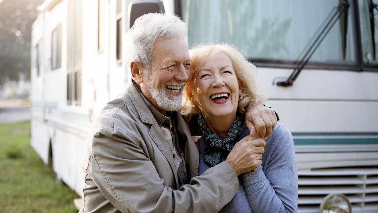 Smilende eldre par utenfor bobil