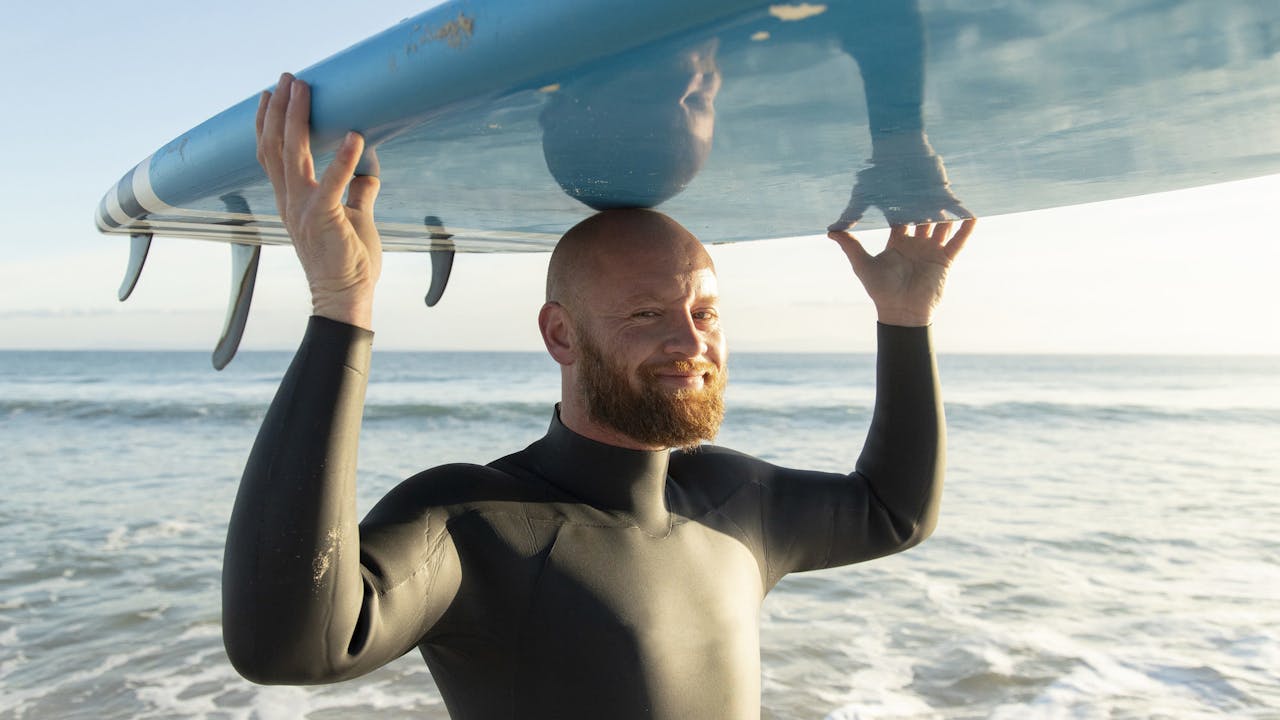 Mann med skjegg og surfebrett på hodet