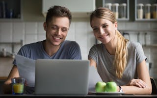 Smilende mann og dame foran laptop