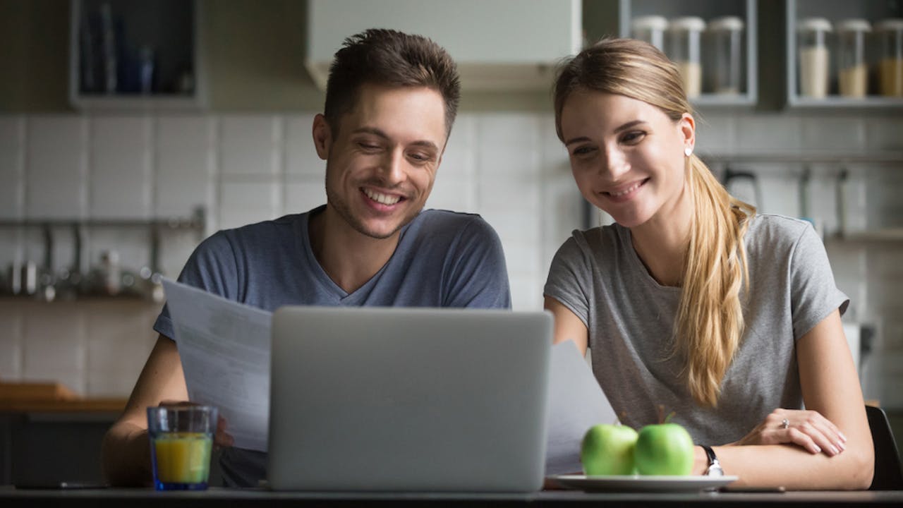Smilende mann og dame foran laptop