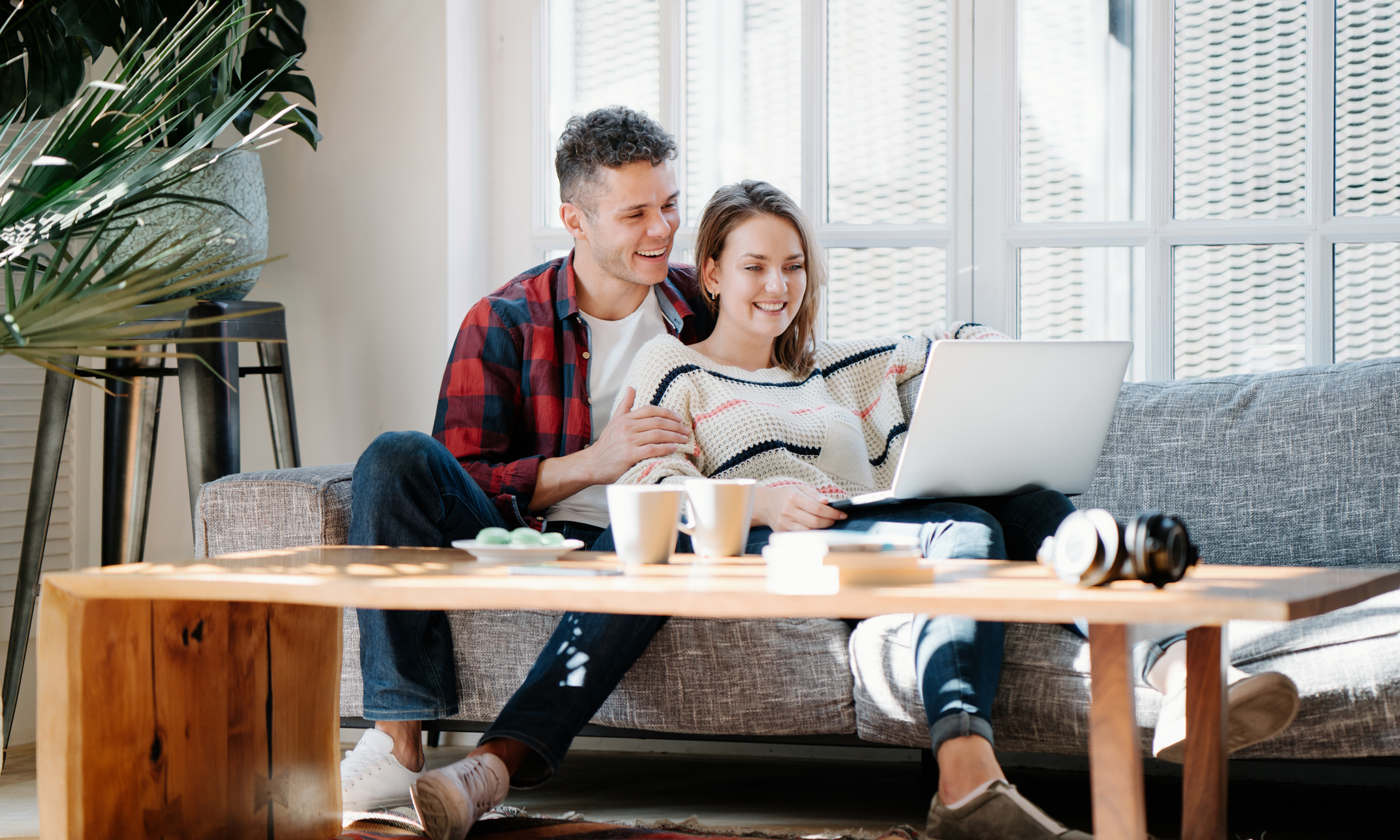 Par sitter i sofa med laptop i fanget