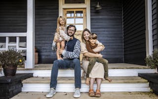 Familie sitter på trapp utenfor hus