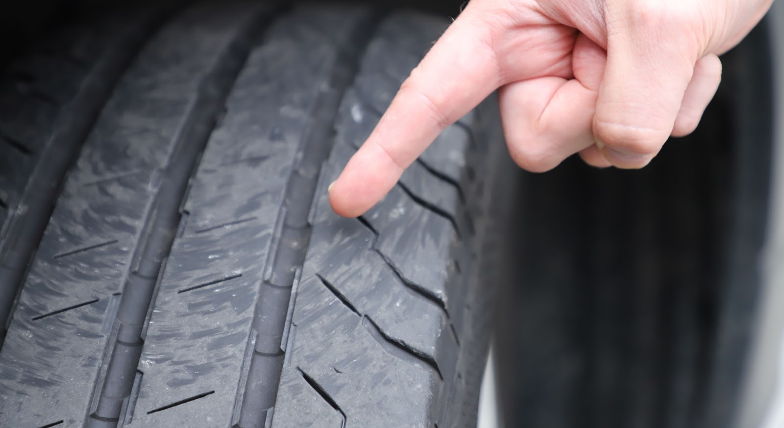 En hånd påpeker mønsterdybde på bildekk