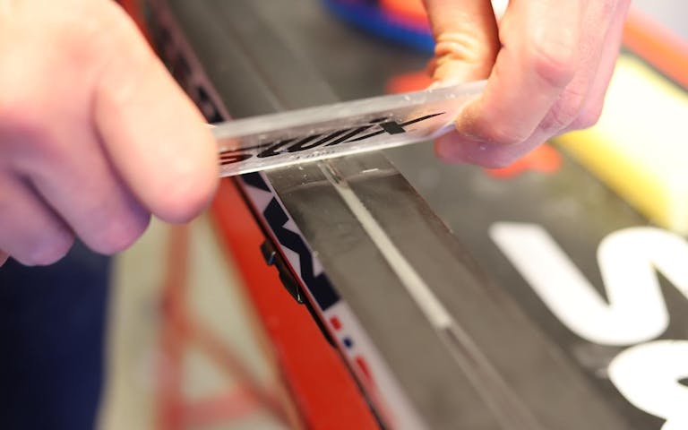 SKRAP VEKK GLIDEREN: Ved hjelp av en plastsikling fjerner du glideren til kun en tynn film ligger igjen over skisålen. Foto: Svein Dybdahl