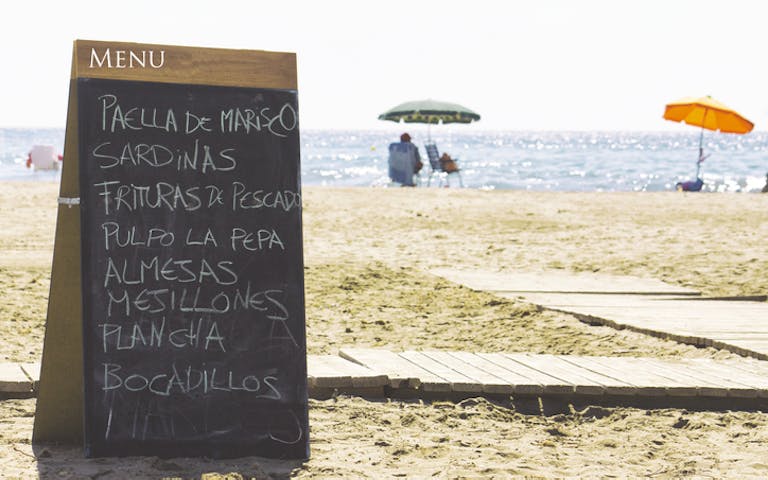 Bilde fra stranden i Valencia med menyskilt fra restauranten