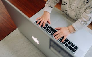 Et barn har hendene på tastaturet til en bærbar datamaskin