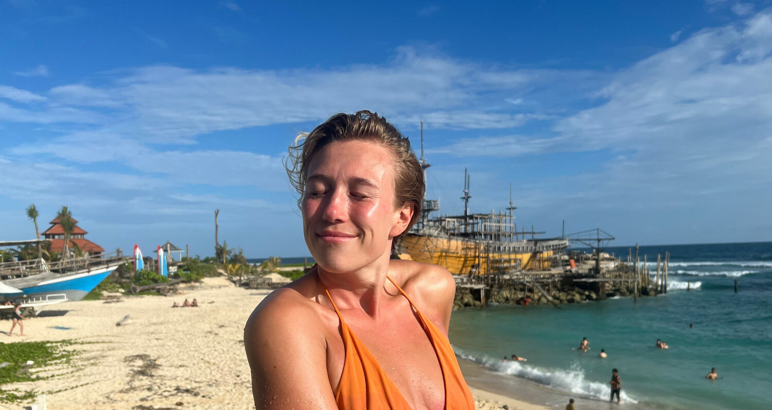 Maria Stavang i oransje bikini soler seg på standen