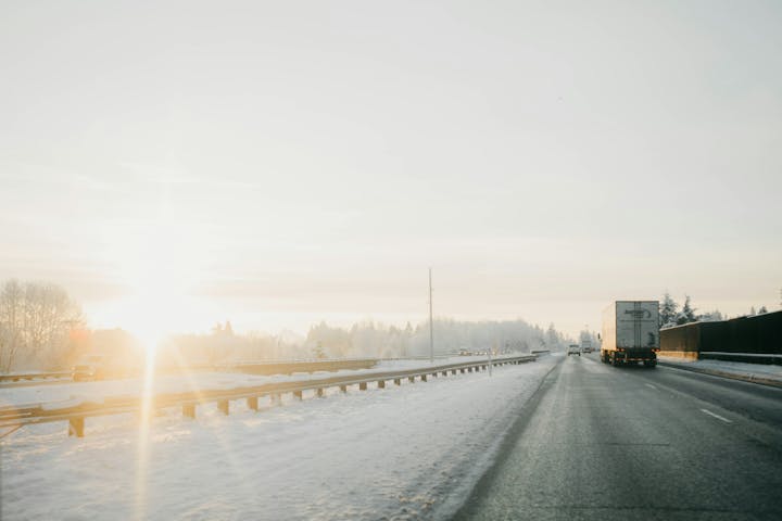 Motorvei med lastebil og andre biler i et snødekt landskap