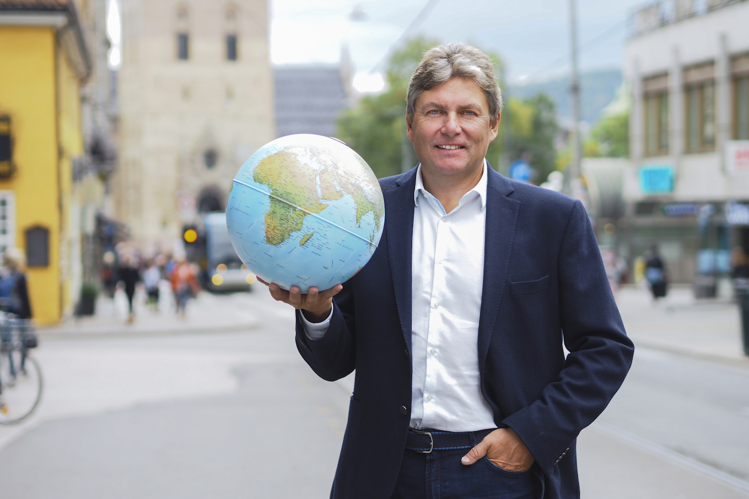 Mann i dress som holder globus